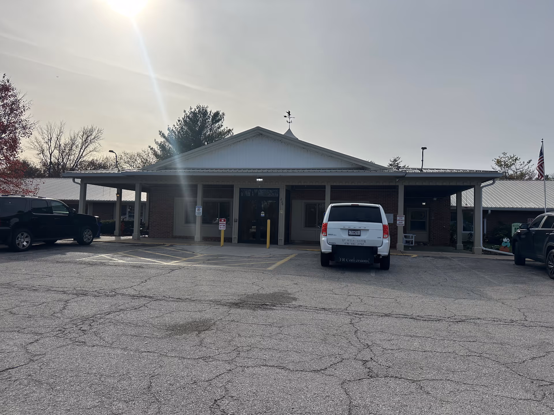 Front exterior of a single-story brick rehabilitation and healthcare building with a covered entrance and cars parked in the lot.