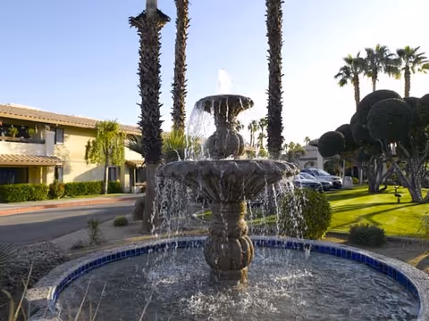 A stone fountain in a landscaped outdoor courtyard outside Atria Hacienda.