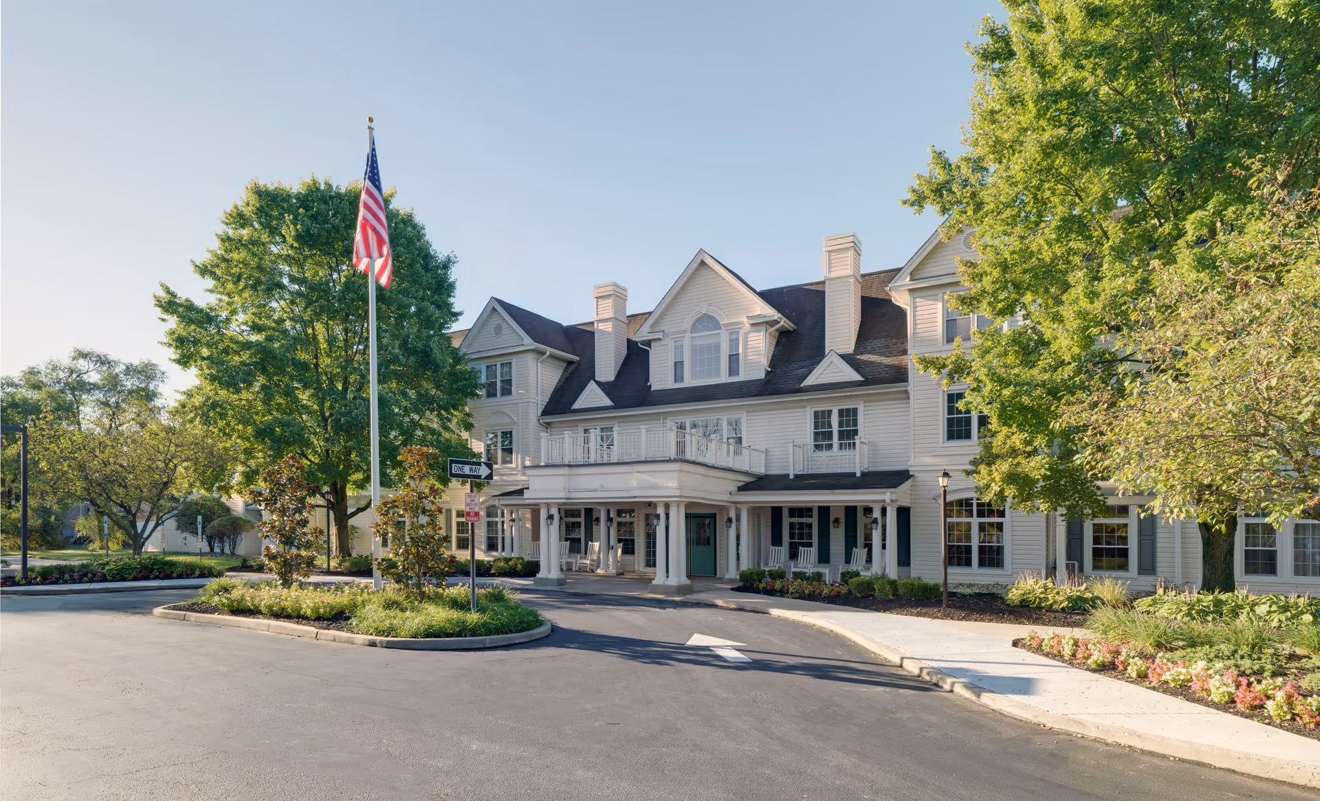Front view of The Residence at Cherry Hill senior living facility with flagpole and landscaping.