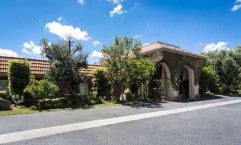 Exterior view of Riverwalk Post Acute facility with arched entrance and greenery.