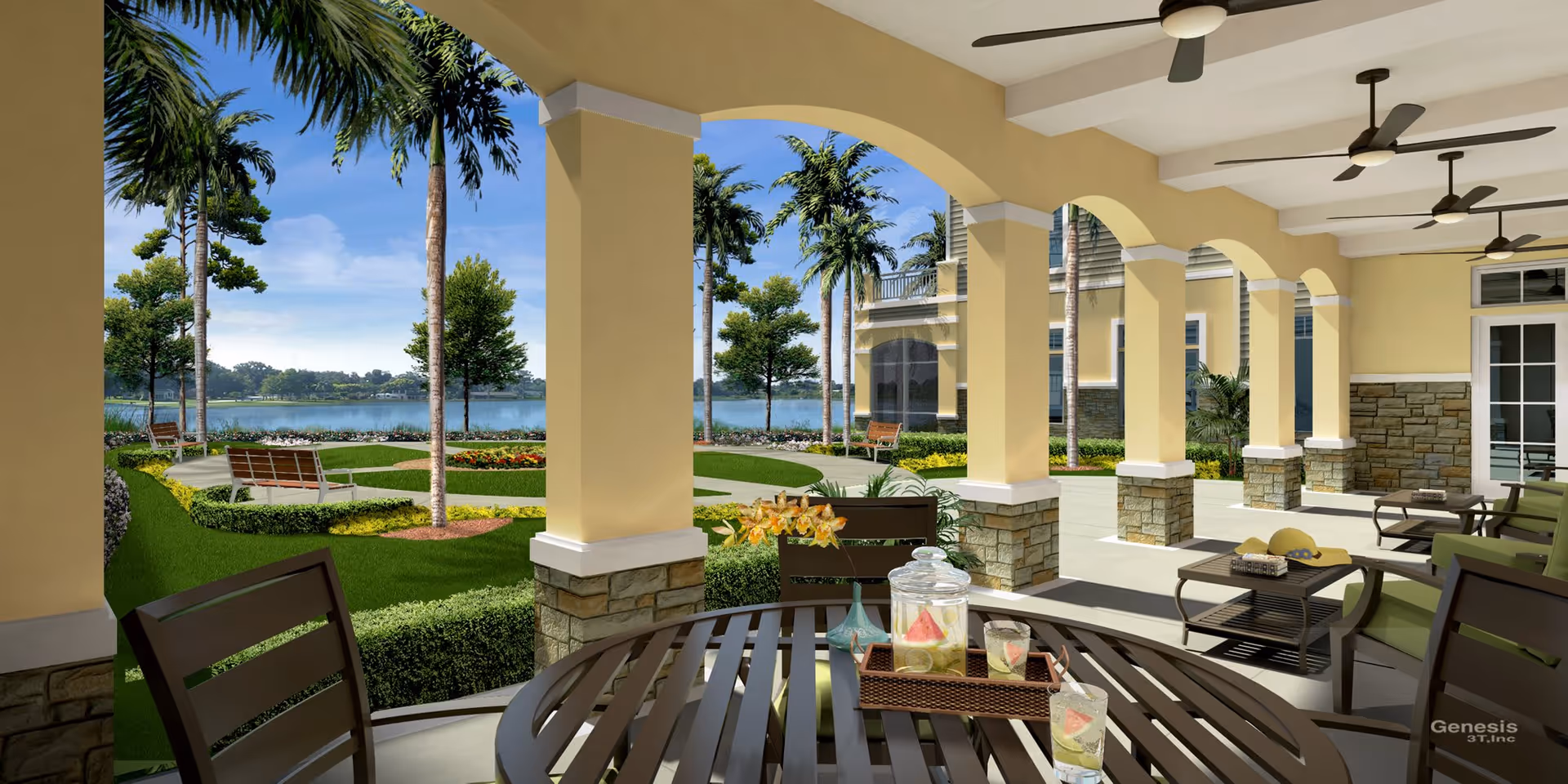 Covered outdoor patio area with a round table and chairs in the foreground, overlooking a landscaped garden with palm trees, benches, and a lake in the background under a clear blue sky.