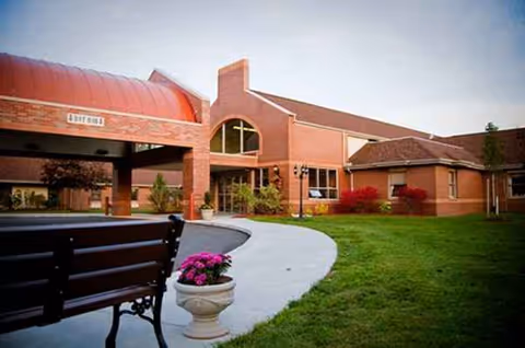 Front exterior of Crawford County Care Center, brick building with curved walkway and bench.
