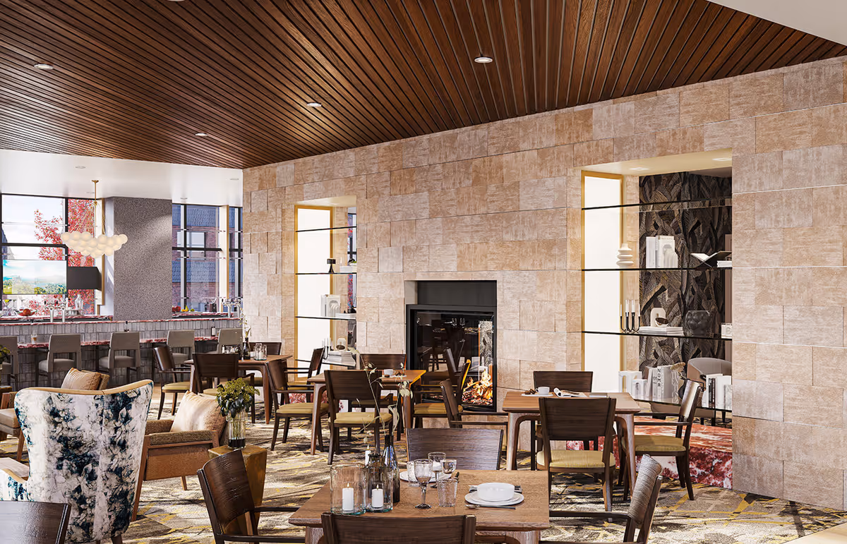 Spacious, well-lit dining room with multiple tables and chairs, a central fireplace, and large windows.