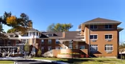 Brick senior living facility with multiple connected wings, a ramped entrance and landscaped planters under a clear blue sky.