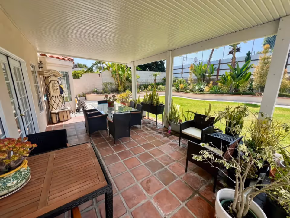A view of a covered outdoor patio with plants and seating at Cabrillo Guest Home, Inc.
