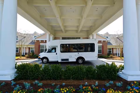 White shuttle bus parked under a covered entrance at The Palmettos of Parklane.