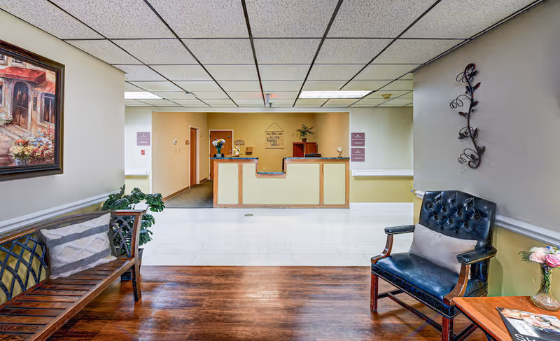 Reception lobby with a front desk, bench seating, armchair, and wall decorations.