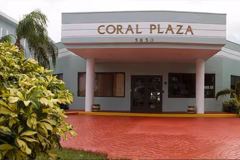 The Coral Plaza facility entrance with pink columns and a red brick driveway.