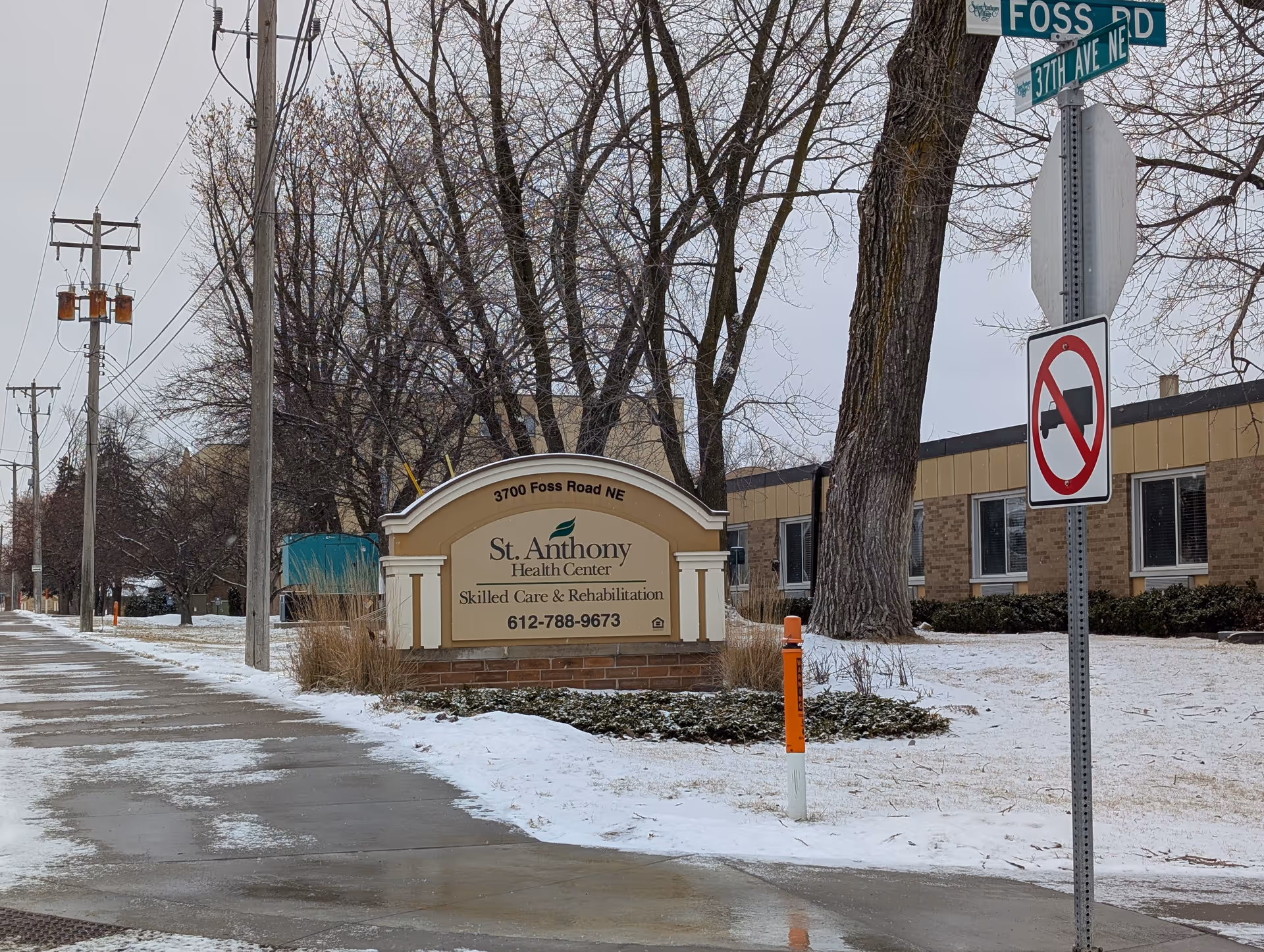 Street view of the St. Anthony Health Center entrance sign and front of the building with snow on the ground.