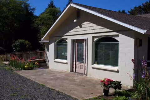 Front exterior of a care home with entrance doors and garden plants.