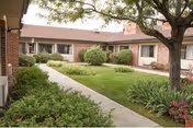 Outdoor courtyard of Garden Terrace at Aurora with a brick building, lawn, and shrubs.