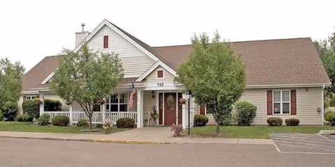 Single-story facility exterior with a covered entrance and two trees in front.