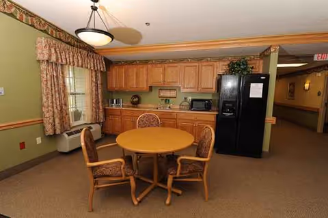 This cozy dining area features a round table, four chairs, and an adjacent kitchenette.