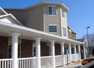Exterior view of a brick senior living facility with a long white-columned porch.