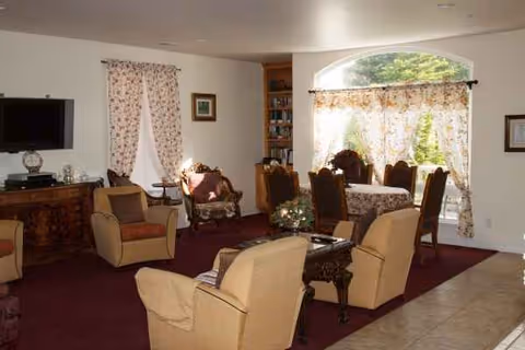 Cozy senior living room with beige chairs, tables, shelves, and floral curtains.
