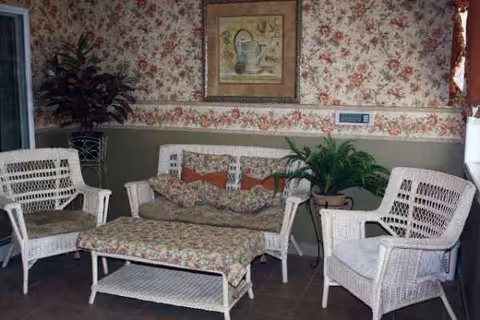 Wicker chairs and a cushioned ottoman arranged in a floral-patterned indoor lounge.
