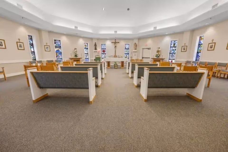 Empty chapel interior with pews facing an altar and crucifix in a senior living facility.