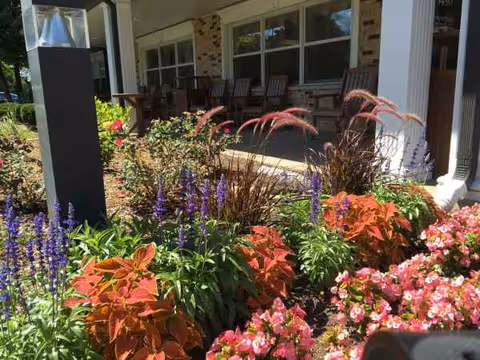 Front porch of The Pearl of Downers Grove with colorful flowers and outdoor seating.