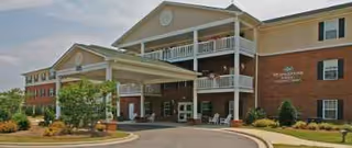 Exterior view of Weatherstone Spring senior living facility with a covered entrance and brick facade.