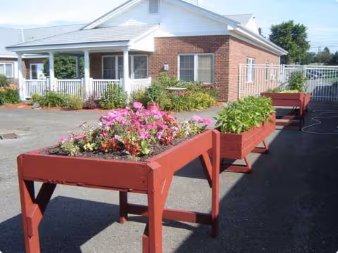 Outdoor scene at Presque Isle Rehab and Nursing with red planters filled with flowers.