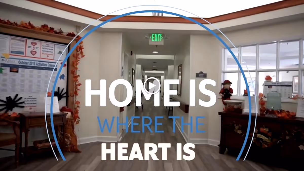 Decorated senior living reception area and central hallway with a 'HOME IS WHERE THE HEART IS' text overlay.