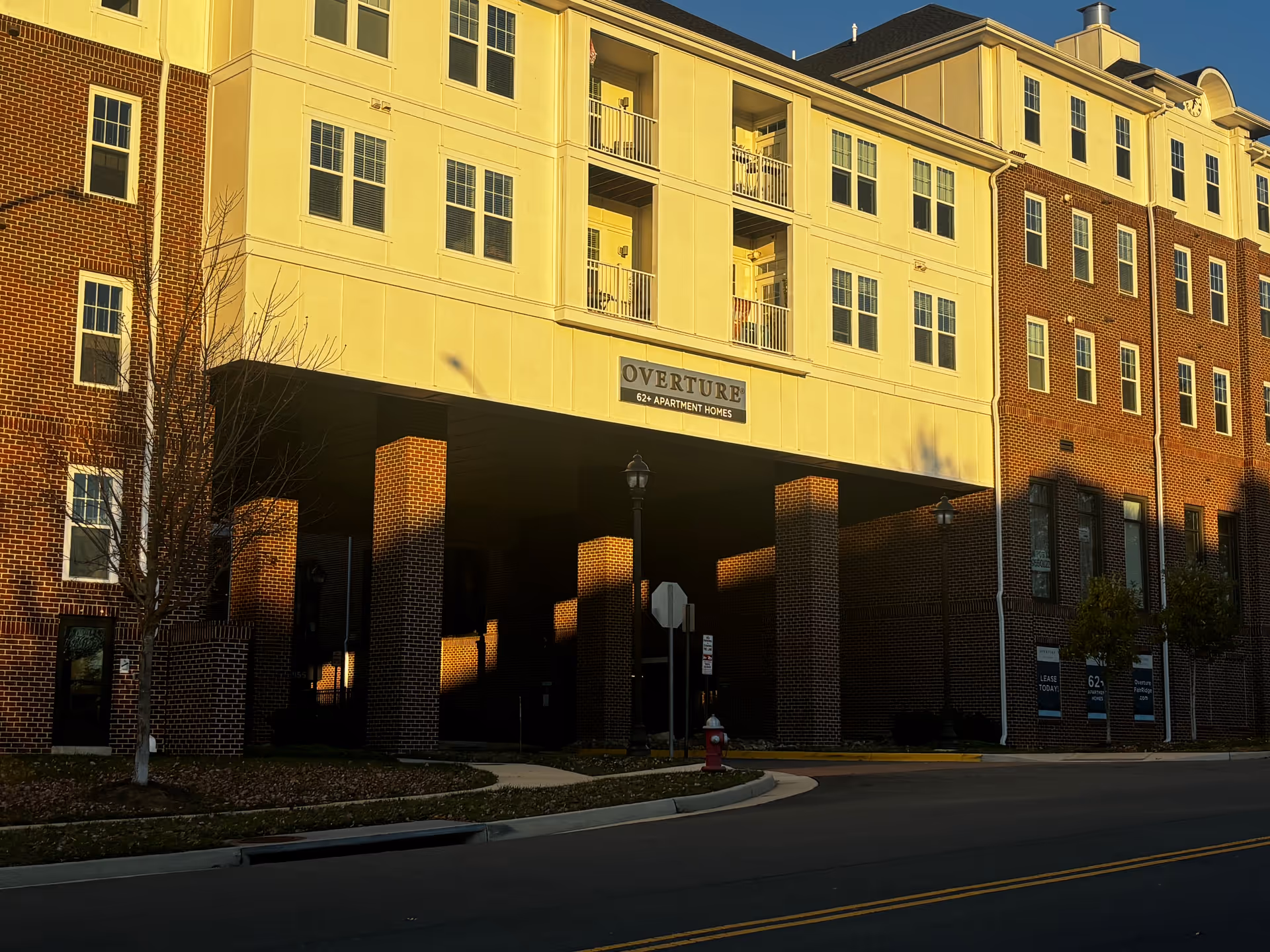 Exterior front of the Overture apartment building with brick façade, a covered entry supported by pillars and a sign reading "OVERTURE".