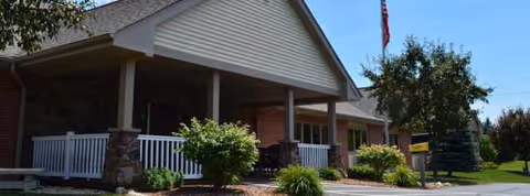 Front view of Touchstone Living Center entrance with porch, landscaping, and flag.