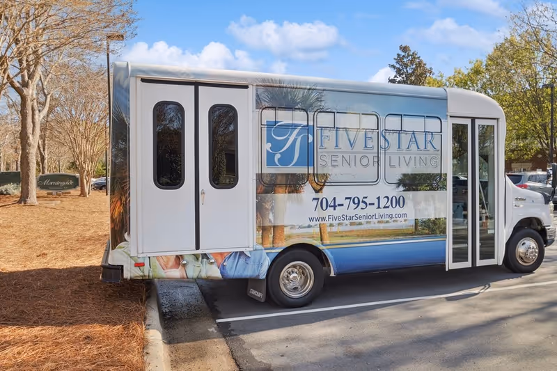 A branded Five Star Senior Living shuttle bus parked outside Morningside of Concord with the company logo and phone number visible.