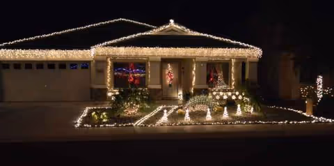 Front exterior of a single-story home decorated with Christmas lights along the roof and walkway.