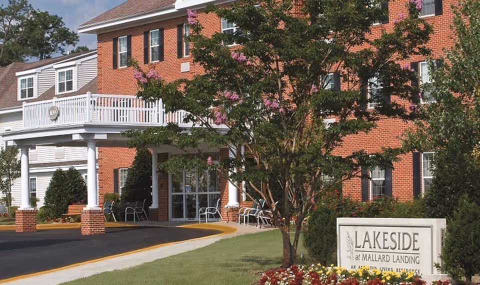Brick-front senior living facility entrance with a covered portico, landscaping, and a 'Lakeside at Mallard Landing' sign.