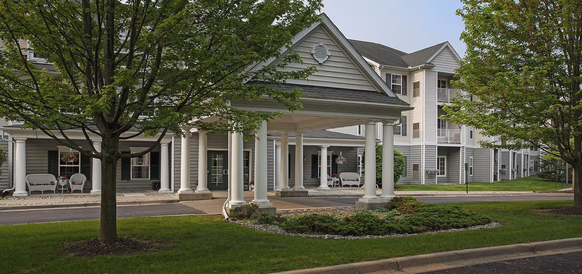 Exterior view of a senior living facility with covered entrance and white columns.