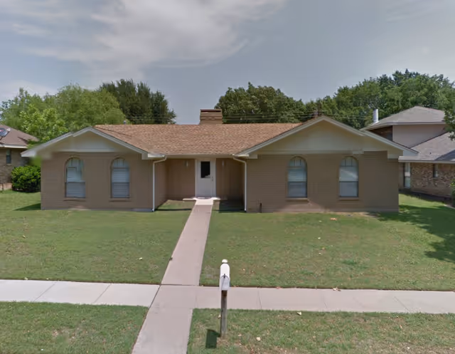 Single-story brick ranch-style house with a central walkway, front lawn, and mailbox.