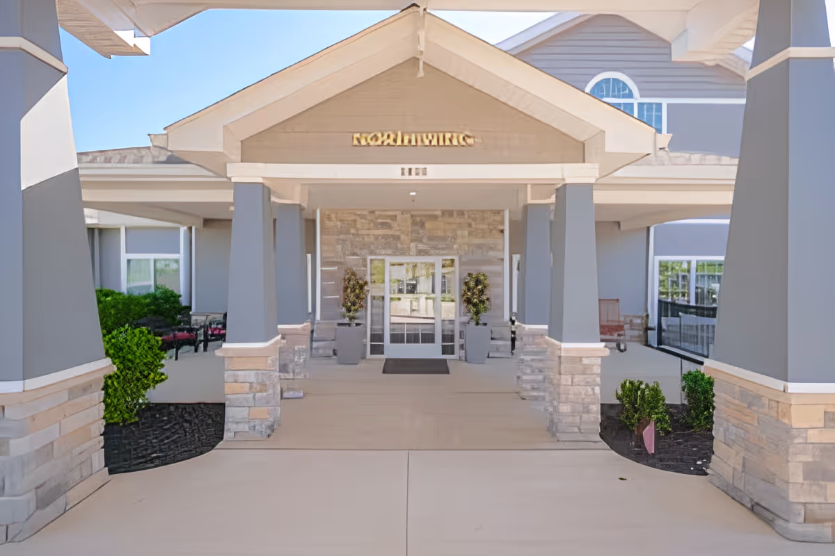 Covered entrance with columns, stone accents, potted plants and glass double doors of the Quality Care of Howell building.