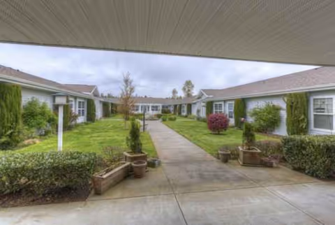 Courtyard walkway between single-story Avista Senior Living Ferndale buildings with greenery.