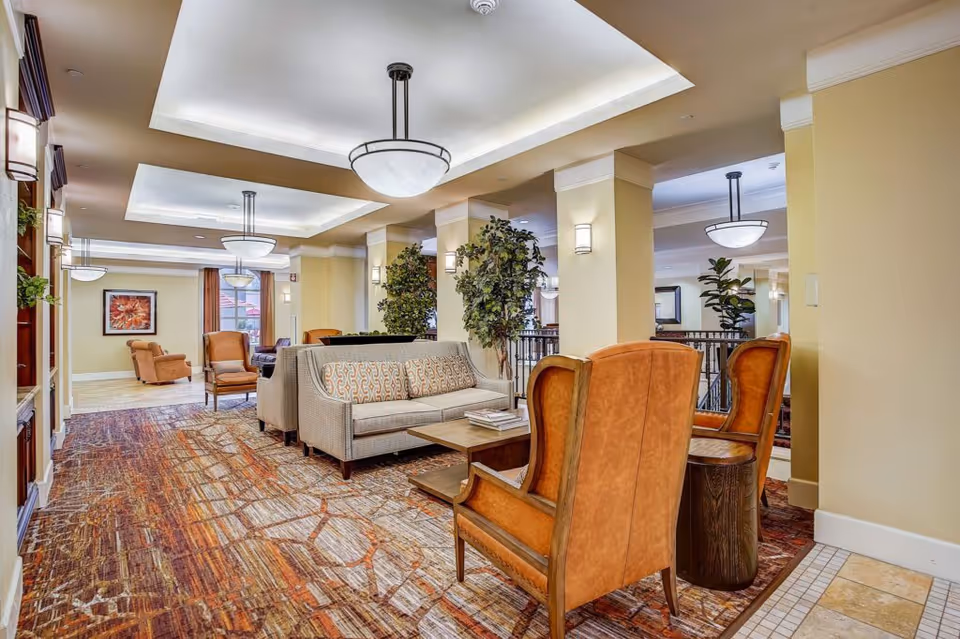 Comfortable communal lounge with sofas and armchairs arranged around coffee tables under recessed ceiling lights.