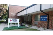 Exterior view of Mendota Lutheran Home building showing a brick facade with a sign in front that reads 'Mendota Lutheran Home' and another sign on the building that says 'Love & Ageless, Visit Us.'