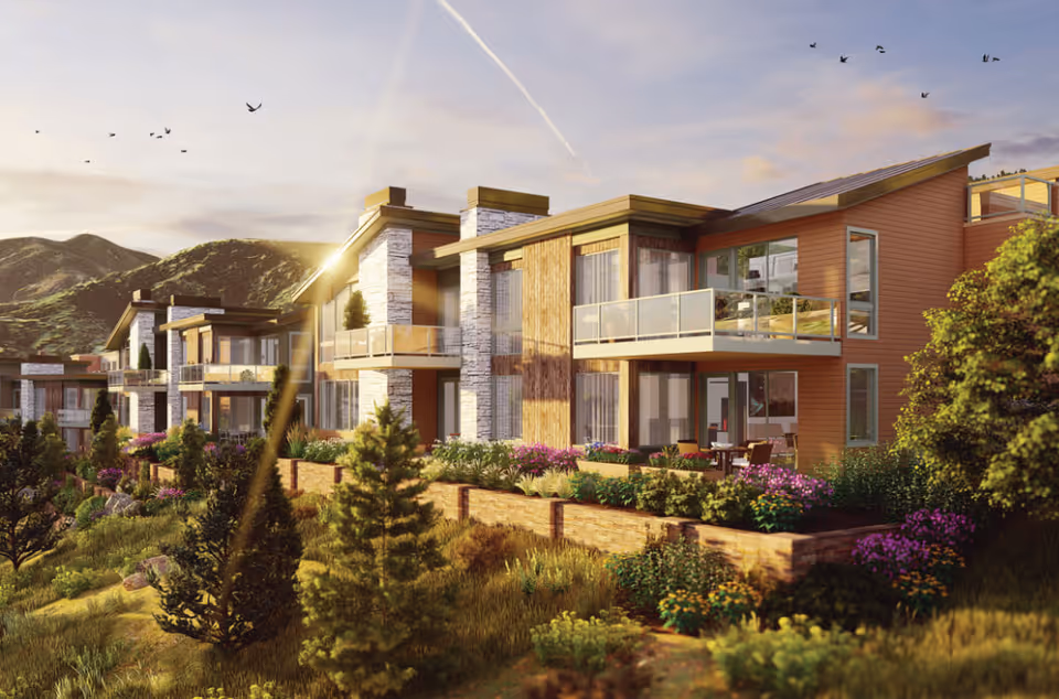 Modern multi-unit residential building with balconies and landscaped gardens set against hills at sunset.