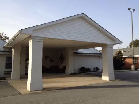 Exterior view of Laurelwood Health Care Center entrance with white columns and driveway.