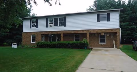 Two-story Miller's Assisted Living exterior with brick lower level, white siding, and a driveway.