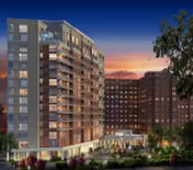 Exterior view of a multi-story senior living facility named Goodwin House Bailey’s Crossroads at sunset, featuring well-lit windows, balconies, and landscaped grounds with trees and bushes.
