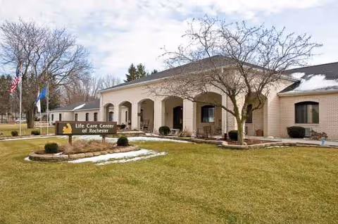 Front view of Life Care Center of Rochester building with arched entrance and lawn