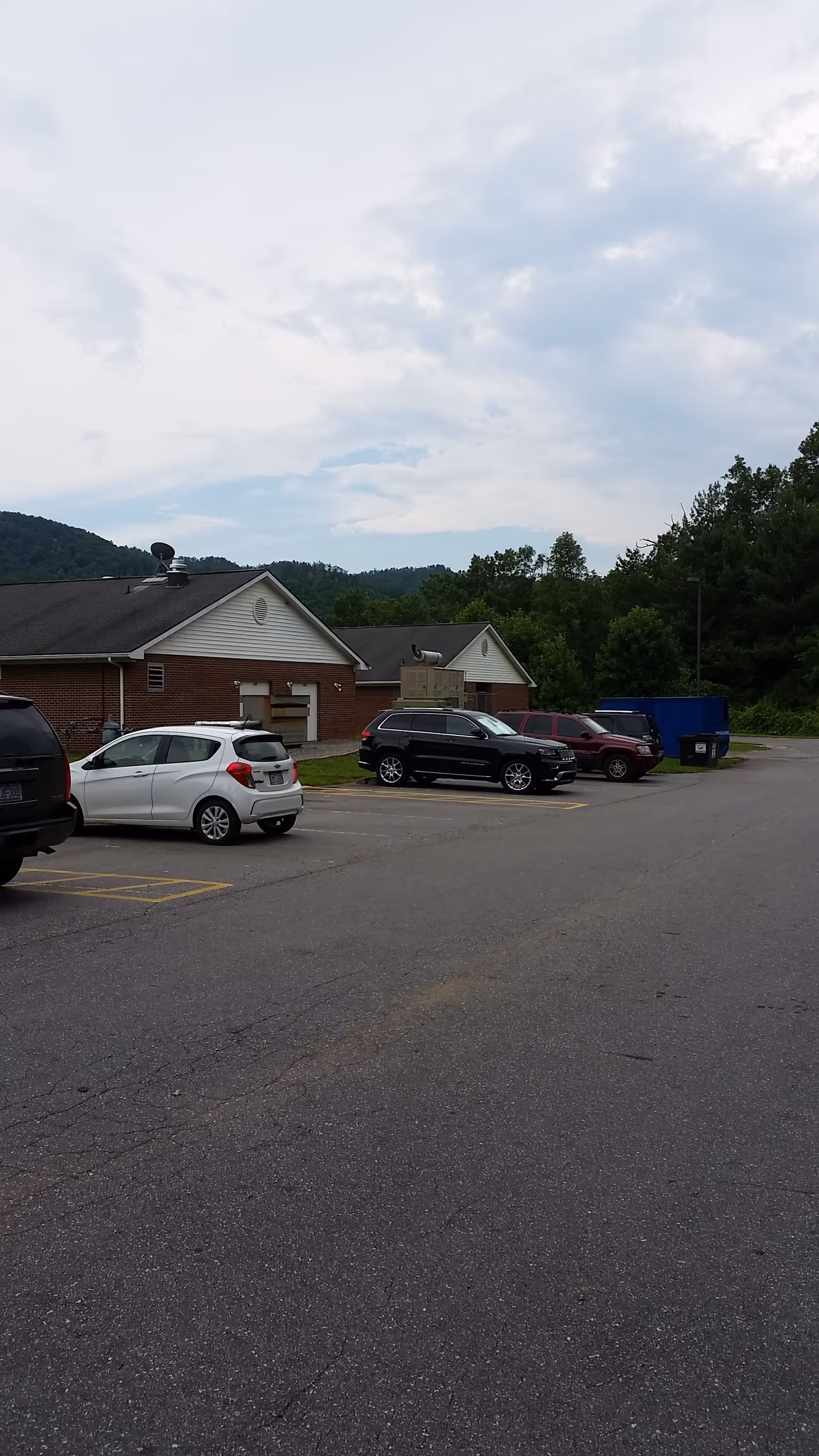 Parking lot with cars in front of a brick Mountain Ridge Wellness Center building.