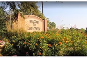 A stone sign surrounded by lush greenery and colorful flowers that reads 'Welcome to Clay Center' under a clear blue sky.