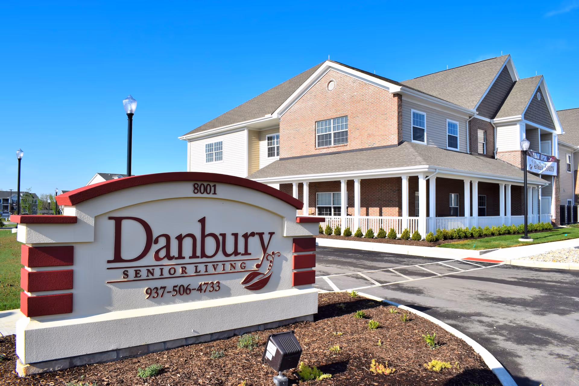 Exterior view of Danbury Senior Living showing a large sign and brick-front building.