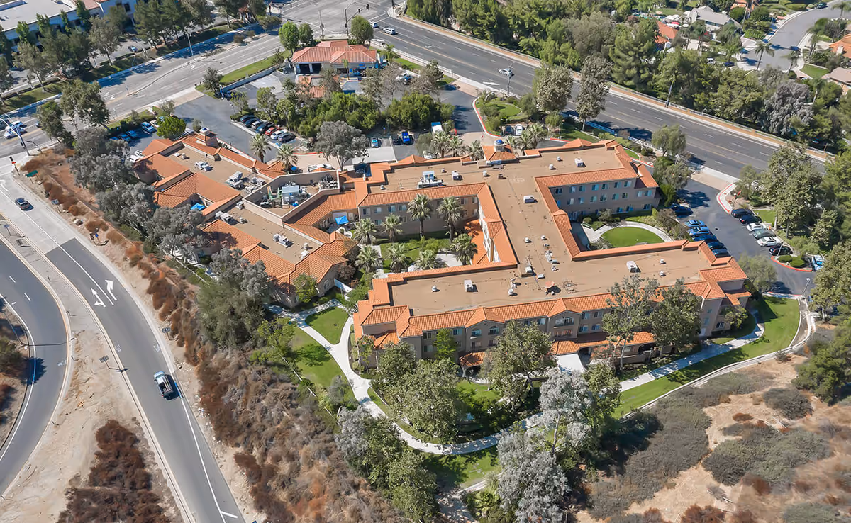 Aerial view of the Bayshire San Dimas senior living complex with terracotta roofs, landscaped courtyards, parking areas, and surrounding roads.