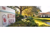 Exterior view of Autumn House senior living facility with sign and landscaped front yard
