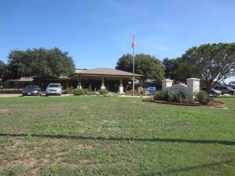 Exterior view of Silver Pines Nursing and Rehabilitation Center with a flagpole and cars.
