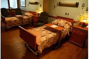 Shared bedroom with two adjustable hospital-style beds, nightstands with lamps, and armchairs.