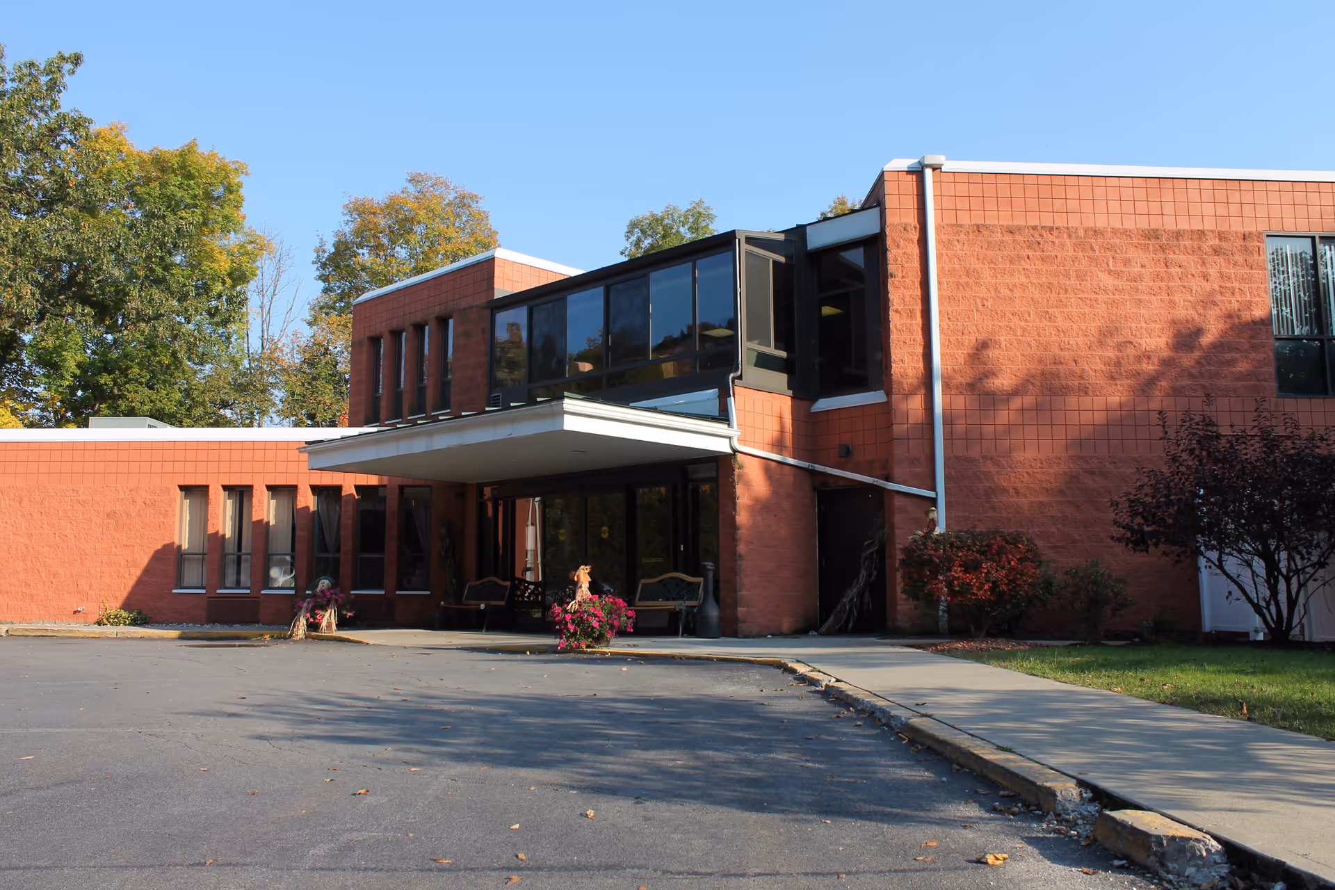 Exterior view of a red-brick senior living facility with large windows and a covered entrance.
