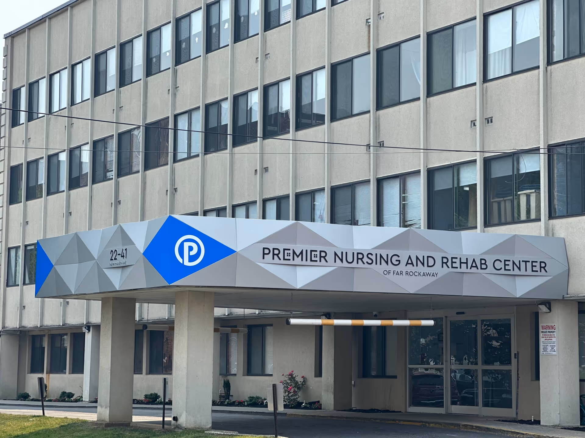Entrance canopy and facade of the Premier Nursing and Rehab Center of Far Rockaway with multiple windows above.